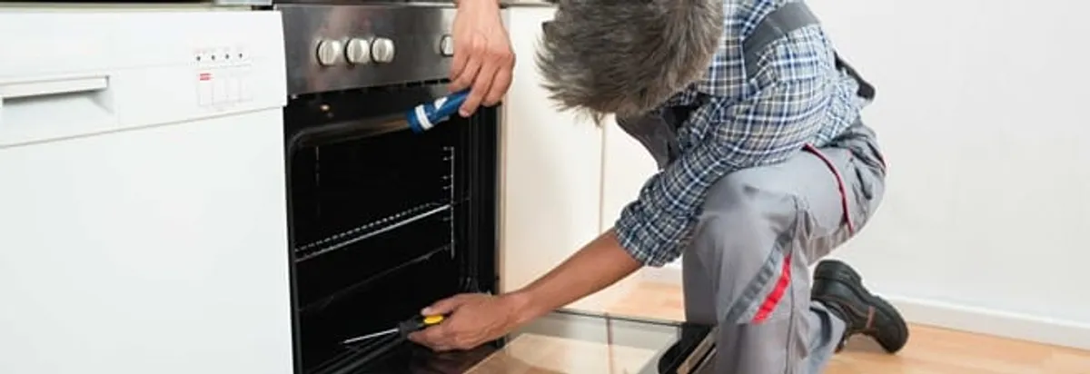 Oven repair technician inspecting and servicing an electric oven in Sarasota, FL