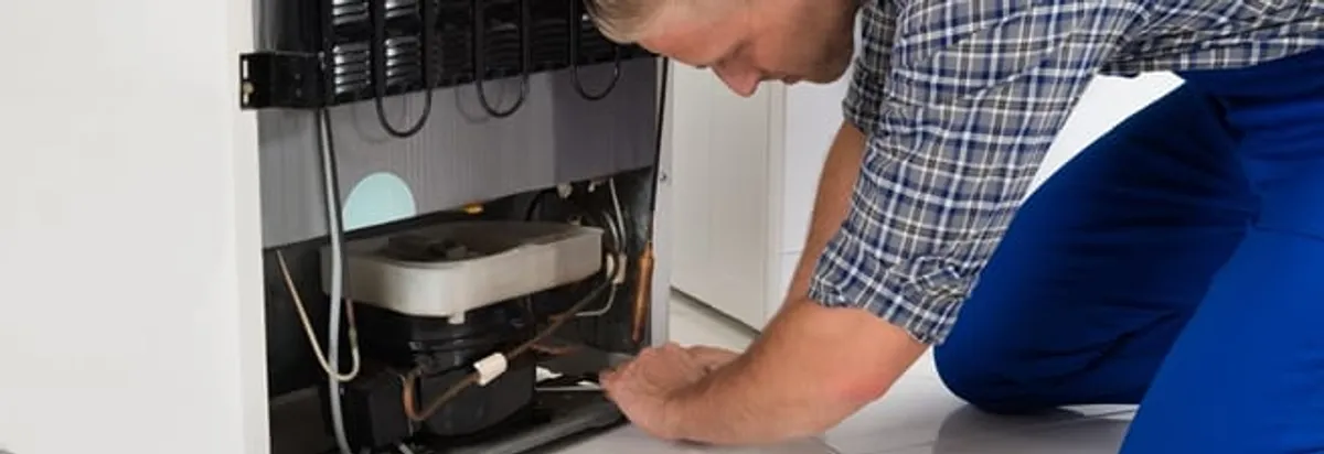 Refrigerator repair technician servicing the compressor and condenser area in Sarasota, FL