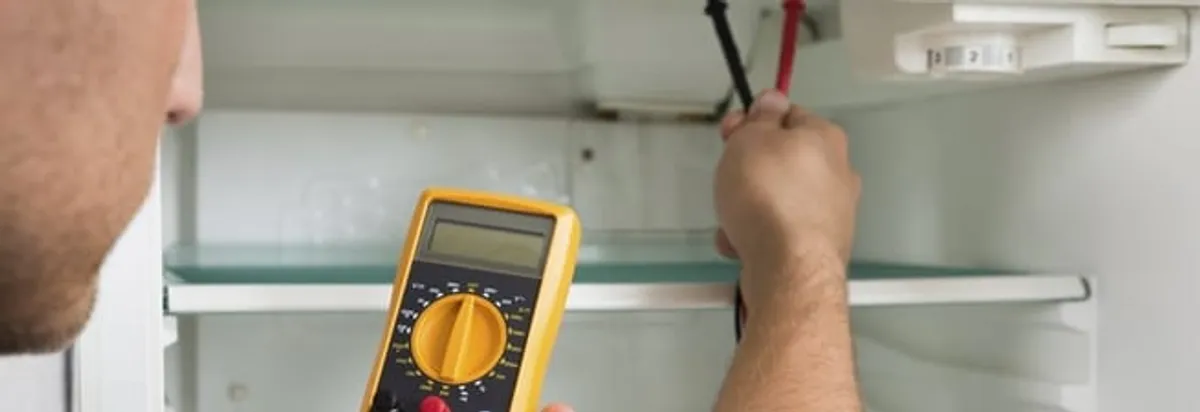Refrigerator repair technician testing electrical components with a multimeter in Sarasota, FL